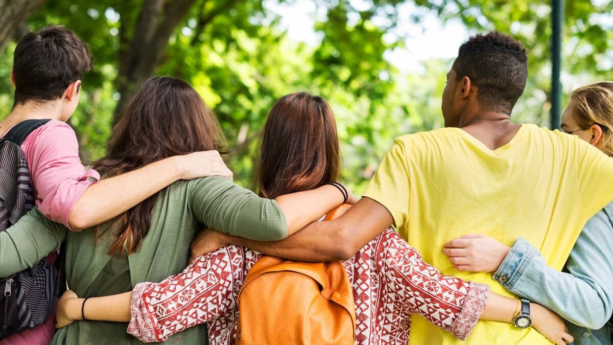 Mehrere Menschen stehen nebeneinander mit ihren Armen über den Schultern der Nebenstehenden